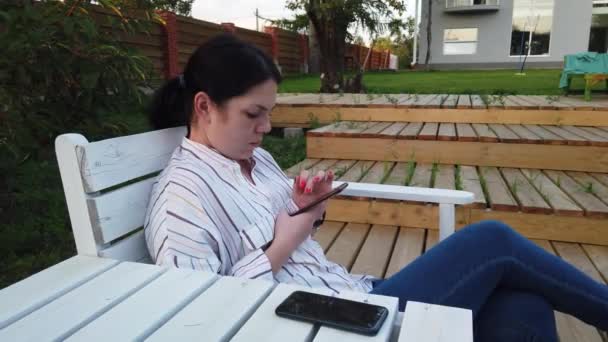 Mujer Uso Del Teléfono Móvil Sentarse Banco Patio Casa — Vídeo de stock