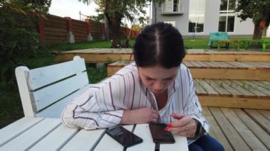 Cep telefonu kadın kullanımı ve bahçesinde evde bankta oturup