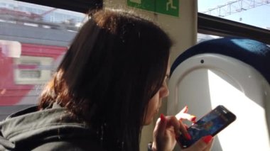 Trendeki kız ve bir akıllı telefon. Seyahat taşımacılığı demiryolu konsepti. Pencerede trende kız pencerede tren vagonundaki kıza karşılık gelir..