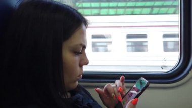 Trenvagongüzel genç kız koltuklar ve akıllı telefon kullanmak, arkadaşlarınıza mesaj mesajlaşma ve pencereden bakarak