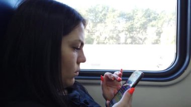 Trenvagongüzel genç kız koltuklar ve akıllı telefon kullanmak, arkadaşlarınıza mesaj mesajlaşma ve pencereden bakarak