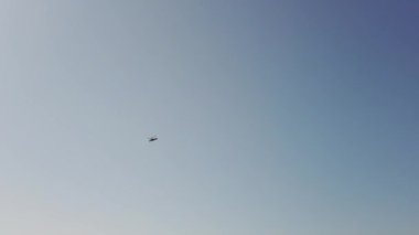 Savaş alanında askeri helikopter yavaş çekimde geçerek havai uçar. Mavi gökyüzü ve bulutlar. 4k Uhd yavaş çekim ham video görüntüleri 60 fps
