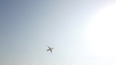 Gökyüzünde uçan büyük beyaz ve mavi yolcu uçağı. Mavi gökyüzü arka planına sahip siluet içinde yükselen bir uçak. Modern ulaşım ve havacılık. Yolcu jet uçağı gösteri uçuşunu gerçekleştiriyor..