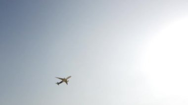 Gökyüzünde uçan büyük beyaz ve mavi yolcu uçağı. Mavi gökyüzü arka planına sahip siluet içinde yükselen bir uçak. Modern ulaşım ve havacılık. Yolcu jet uçağı gösteri uçuşunu gerçekleştiriyor..