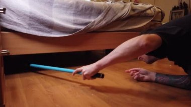 Genç adam evde yerleri yıkıyor. Bir adamın ahşap zemindeki kiri özel bir bezle temizlerken..