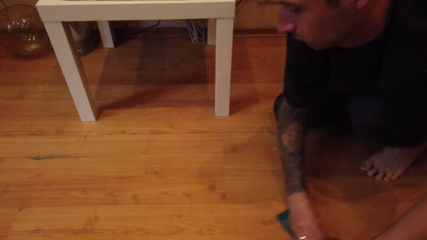 若い男が家で床を洗っている 特別な布で床から男の拭く汚れの閉鎖 — ストック動画