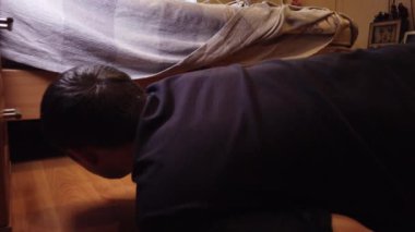 Genç adam evde yerleri yıkıyor. Bir adamın ahşap zemindeki kiri özel bir bezle temizlerken..