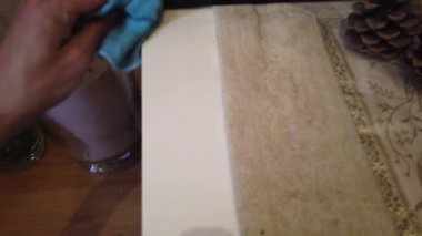 Bir adamın eli, özel bir bezle ahşap bir masadaki kiri temizliyor.