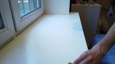 Bir adamın eli, özel bir bezle ahşap bir masadaki kiri temizliyor.