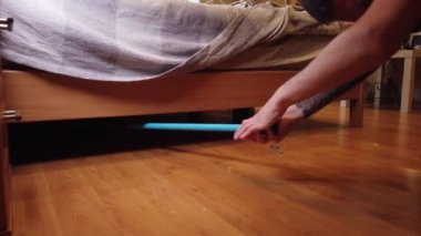 Genç adam evde yerleri yıkıyor. Bir adamın ahşap zemindeki kiri özel bir bezle temizlerken..