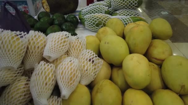 Eladó trópusi vietnami gyümölcsök a piacon. A lány egzotikus gyümölcsöket választ a boltban.. — Stock videók
