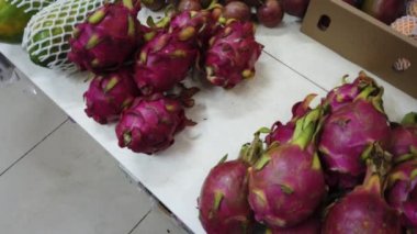 Marketin tezgahında tropikal Vietnam meyveleri satılıyor. Kız dükkanda egzotik meyveler seçiyor..