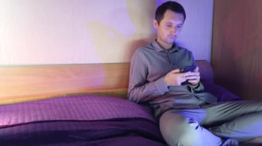 Evde bir adam telefonda oturuyor ve online bir kumarhanede oynuyor, kazanmanın verdiği duygular.