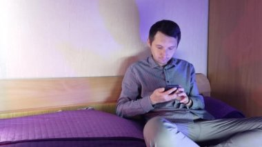 Evde bir adam telefonda oturuyor ve online bir kumarhanede oynuyor, kazanmanın verdiği duygular.