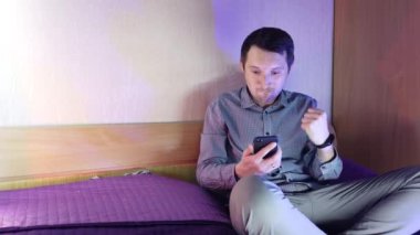 Evde bir adam telefonda oturuyor ve online bir kumarhanede oynuyor, kazanmanın verdiği duygular.