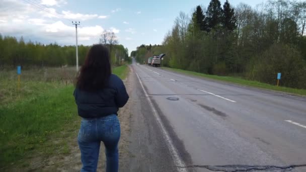 Dziewczyna Idzie Pustą Drogą Próbuje Złapać Autostopem — Wideo stockowe