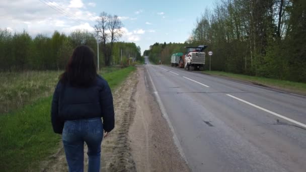 Flicka Går Längs Tom Väg Och Försöker Fånga Bil Liftar — Stockvideo