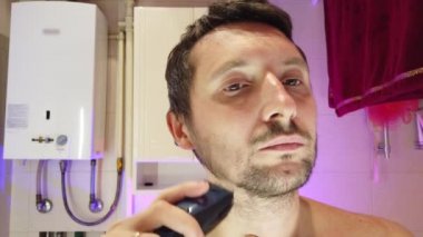 Banyoda bir adam tıraş olur, şarkı söyler ve aynı anda dans eder.