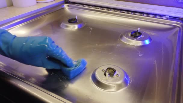 一个戴蓝色手套的男人在厨房里给煤气炉上光 — 图库视频影像