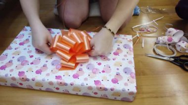 Kız ateşi çok renkli bir kağıda sarıp turuncu bir papyonla bağlıyor..