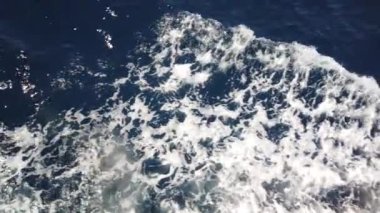 Mavi deniz yüzeyinde yüzen gemiden gelen su izleri. Köpüklü, köpüklü, köpüklü, köpüklü, baloncuklu deniz suyu..