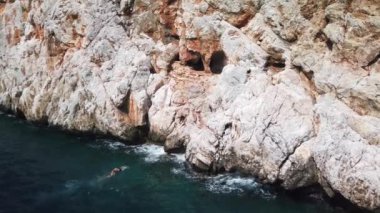 Denizdeki gemi dağın yakınındaki kayalık kıyı boyunca ilerliyor.