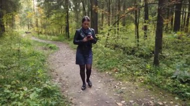 Kız sonbaharda ormanda yürüyor, yapraklar ağaçlarda sararmaya başlıyor.