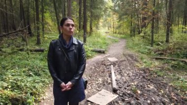 Kız sonbaharda ormanda yürüyor, yapraklar ağaçlarda sararmaya başlıyor.