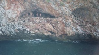 17 Eylül 2020, ANTALYA, TURKEY: Bir grup insan deniz kenarında bir mağarada toplandı ve suya atladı