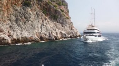 Denizdeki gemi dağın yakınındaki kayalık kıyı boyunca ilerliyor.