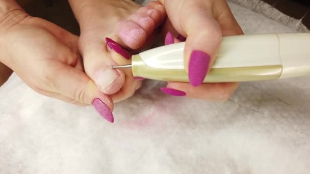 Een meisje thuis doet een pedicure, poetst haar teennagels met een speciale schuurmachine, hardware manicure. — Stockvideo
