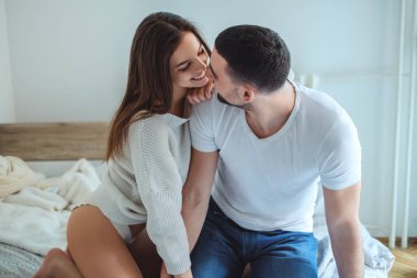 Seksi genç çift yatakta gülümseyen ve birbirine bakarak