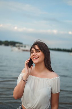 Nehrin yanında telefonda konuşurken gülümseyen güzel esmer kız