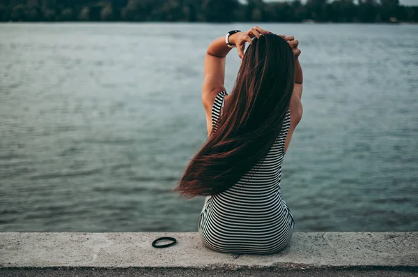 Çekici kız saçını suyun kenarında otururken sabitleme