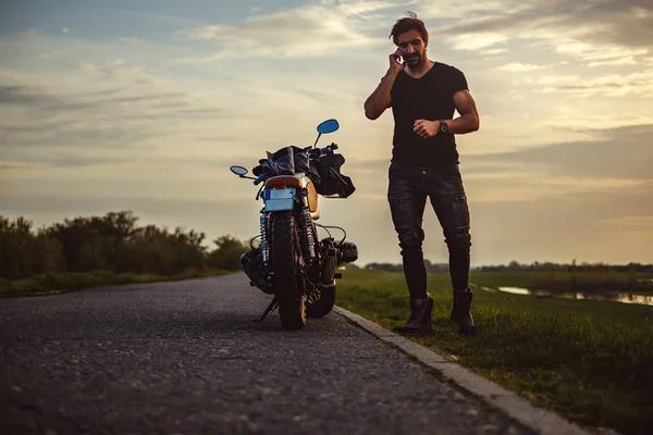 Man talking on the phone by his bike in the middle of the road