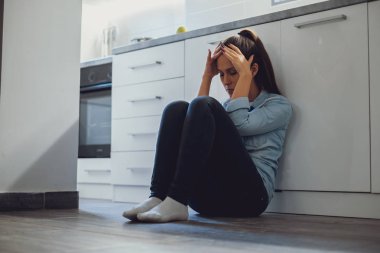 Mutfak katta oturan ve kafasını tutarak depresif kadın