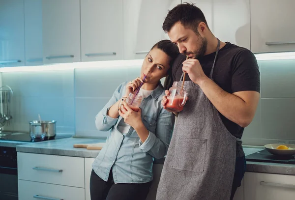 妻子轻轻地倚在她的丈夫在厨房里 而喝冰沙 — 图库照片