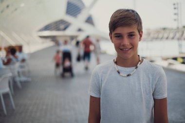 Dışarıda duran gülümseyen yakışıklı bir çocuk portresi