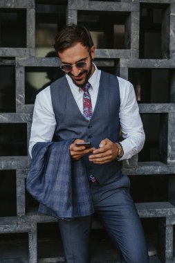 Cep telefonu seyir ve ceketini holding dışında gülümseyen iş adamı