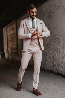 Zarif adam binadan yürürken saatine bakıyor