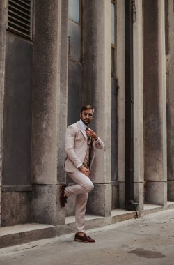 Kravatını sabitleme yakışıklı, şık adam bina duvara yaslandı