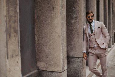 Güneş gözlüğü rahatlatıcı ile yakışıklı işadamı bina duvara yaslandı