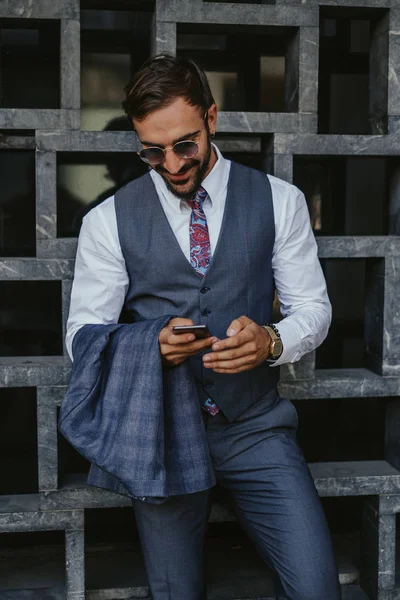 Hombre Negocios Sonriendo Afuera Mientras Mira Teléfono Móvil Sostiene Chaqueta —  Fotos de Stock