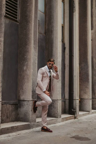 Homem Elegante Olhando Sobre Seus Óculos Sol Enquanto Inclina Parede — Fotografia de Stock