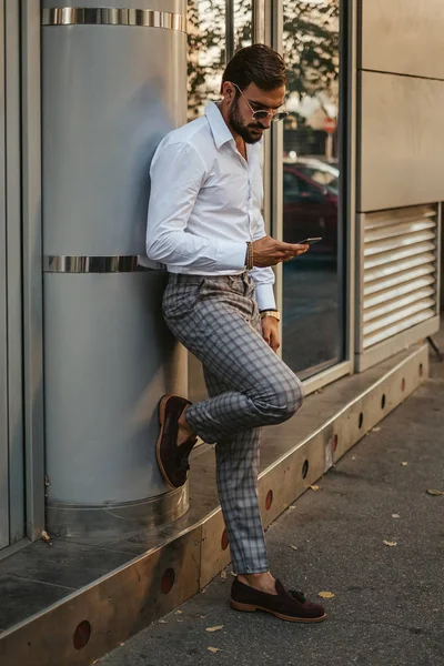 Bonito Homem Barbudo Apoiado Uma Parede Olhando Para Telefone Celular — Fotografia de Stock