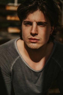 Yüzü güneş ışığı altında olan yakışıklı ve ciddi bir adam portresi. Güzel bir güneşli gün