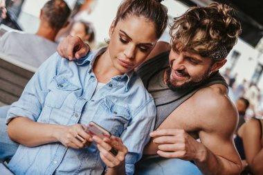 Kızgın kız güzel bir günde bir kafede gülümseyen erkek için cep telefonu gösterilen