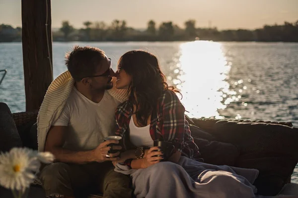 コーヒーを押しながら日没で川でキスのカップル 綺麗で秋の日 — ストック写真