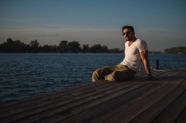 Yakışıklı sakallı adam rahatlatıcı Nehri üzerinde yerleştirin. Güzel bir gün