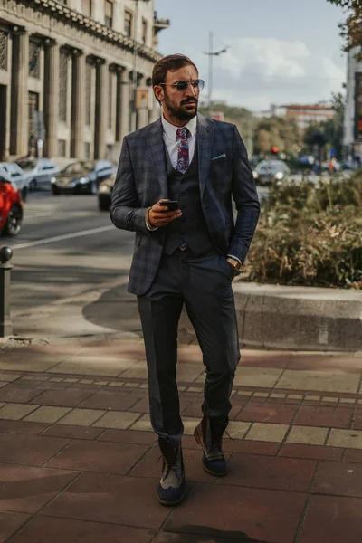 Empresário andando e segurando telefone celular — Fotografia de Stock